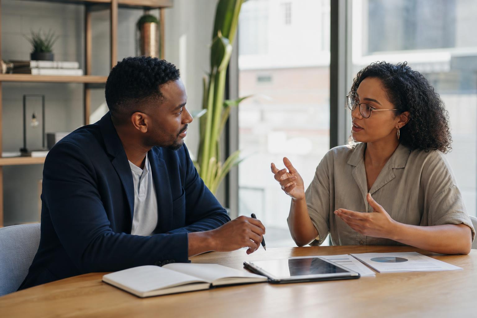 A consultant and a small business owner in thoughtful discussion across a table, reflecting human judgment, strategy, and confident decision-making